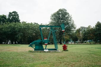 Green pumpjack in a Bangkok park, a fusion of industry and nature.