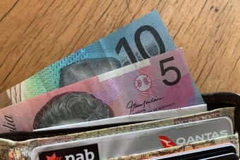 Close-up of Australian dollar bills and credit cards in a wallet on a wooden surface.