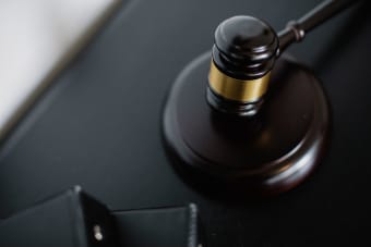From above of wooden gavel on round surface near folders on table in courtroom