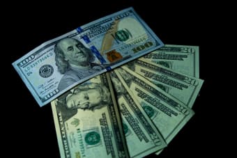 Close-up image of varied US dollar bills on a black background.