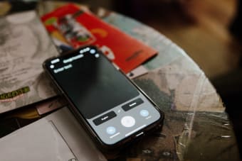 Modern smartphone on cluttered desk with books and notes reflecting daily life.