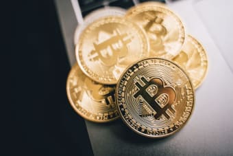 Close-up of golden Bitcoin coins on a laptop keyboard, symbolizing cryptocurrency investment.