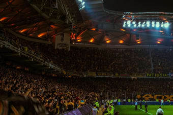 Exciting night soccer game with packed cheering fans and vibrant stadium lights.