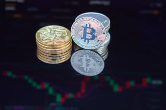 Close-up of bitcoin coins reflecting on a screen with financial market data, highlighting digital currency trend.