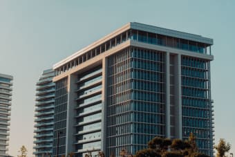 A modern highrise building with glass facade against a clear sky, showcasing urban architecture.