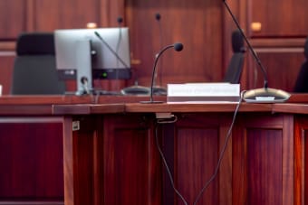 Close-up of a wooden podium with microphones in a Polish courtroom setting.