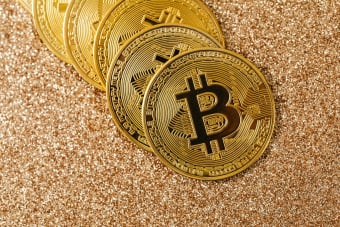 Golden Bitcoin coins arranged on a sparkling glitter surface, symbolizing cryptocurrency and wealth.