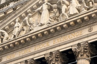 Ornate façade of the New York Stock Exchange featuring intricate stone sculptures during daylight.