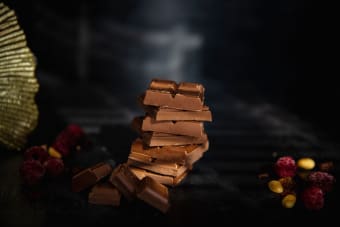 Tempting stack of chocolate pieces accompanied by berries and nuts, perfect for food photography.