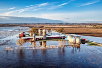 Aerial view of a rural farm with silos and flooded fields in Kellogg, Minnesota showing springtime landscape.