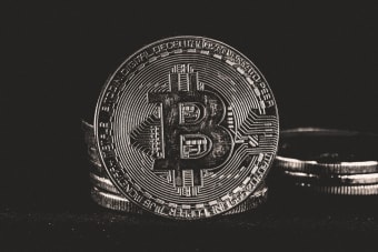 Detailed image of a silver Bitcoin coin on a dark background, highlighting cryptocurrency themes.