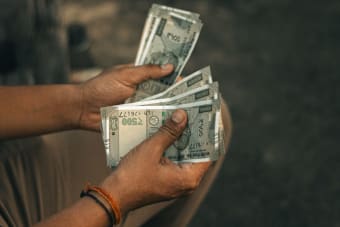 Close-up of hands holding multiple 500 Indian Rupee notes, representing wealth and financial transactions.