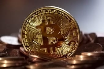 Close-up of a digital cryptocurrency Bitcoin coin placed on a pile of coins.