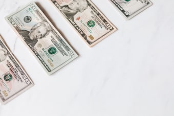 From above of US dollar banknotes in different denominations placed in row on white surface