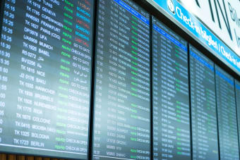 Digital screens display flight information and schedules at an airport terminal.