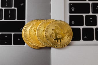 Close-up of Bitcoin coins resting on two laptop keyboards, representing digital currency and technology.