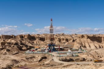 Aerial view of an oil rig amidst desert rock formations, showcasing industrial exploration.