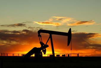 Dramatic silhouette of an oil pump jack against a vibrant sunset sky, emphasizing energy extraction.