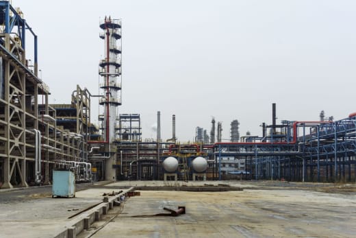 A detailed view of an industrial refinery featuring pipelines and large steel structures.
