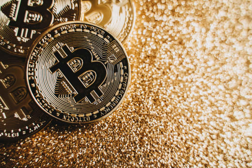 Close-up view of shining Bitcoin coins on a glittering golden background representing digital wealth.