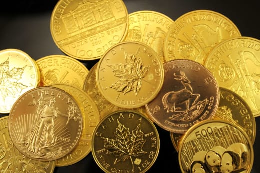 A detailed close-up of diverse gold bullion coins from different countries.