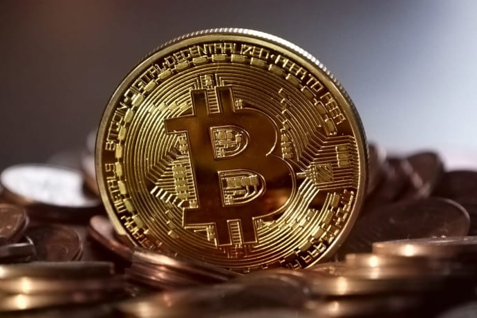 Close-up of a digital cryptocurrency Bitcoin coin placed on a pile of coins.