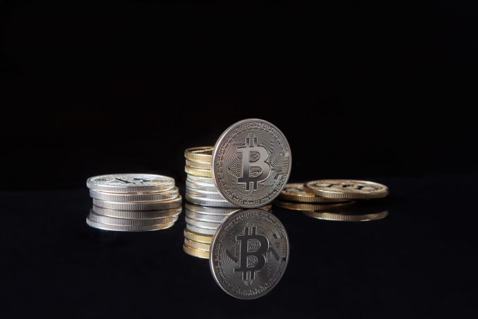 Silver bitcoins stacked on a reflective surface with a dark background, symbolizing cryptocurrency and digital wealth.