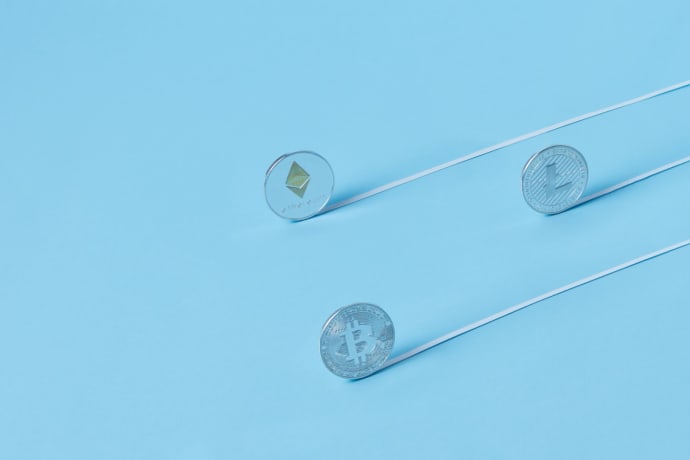 Minimalist image of Bitcoin, Ethereum, and Litecoin coins on a baby blue background.