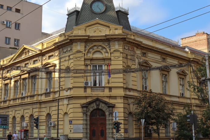 A historic bank building in city center with people walking, showcasing classic architecture.