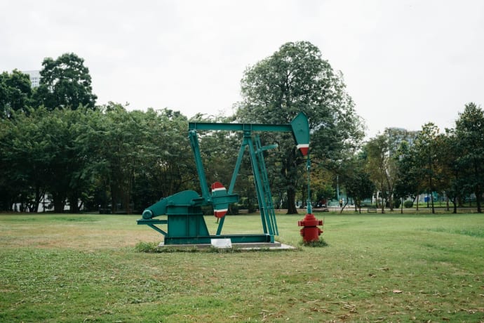 Green pumpjack in a Bangkok park, a fusion of industry and nature.