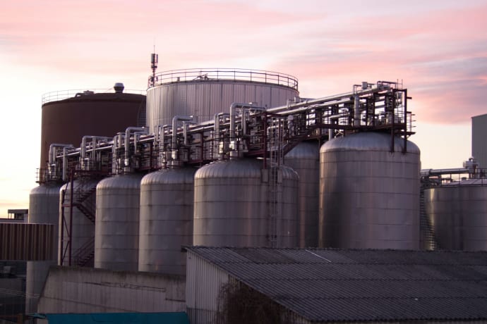 A refinery with large stainless steel storage tanks during sunset, showcasing industrial infrastructure.