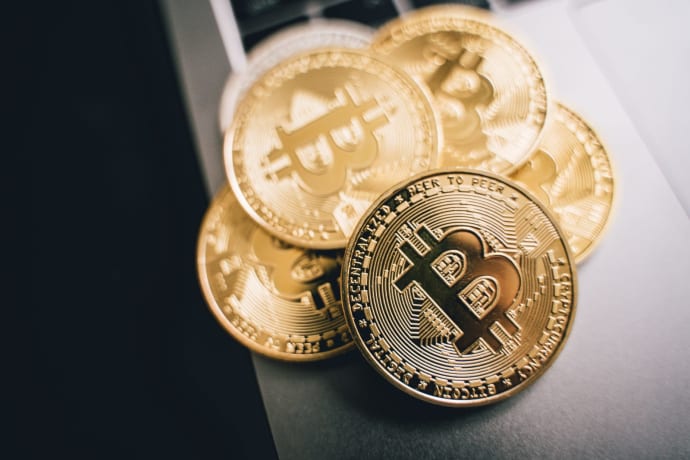 Close-up of golden Bitcoin coins on a laptop keyboard, symbolizing cryptocurrency investment.