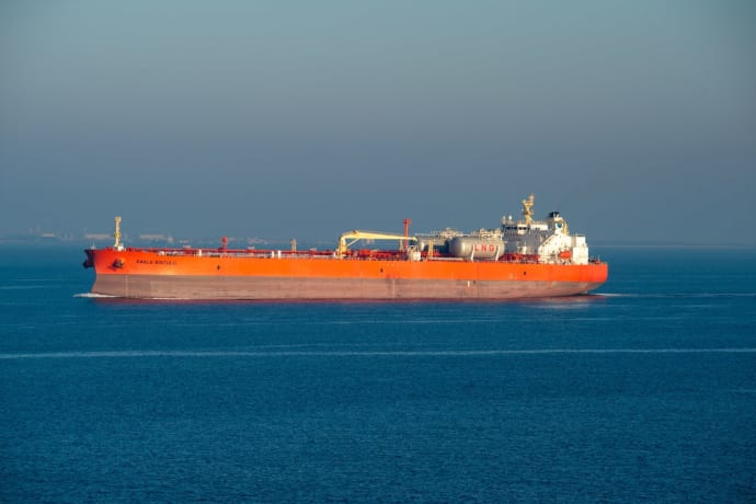 Bright orange LNG carrier ship cruising through calm sea waters on a clear day.