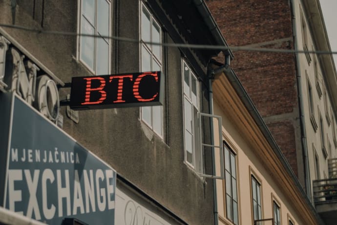 Exterior of a building featuring a prominent BTC and exchange sign, indicating a cryptocurrency location.