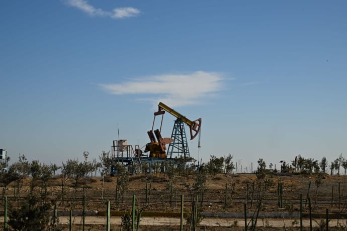 Oil pump jack in a dry landscape with shrubs and clear sky in Bakú, Azerbaijan.