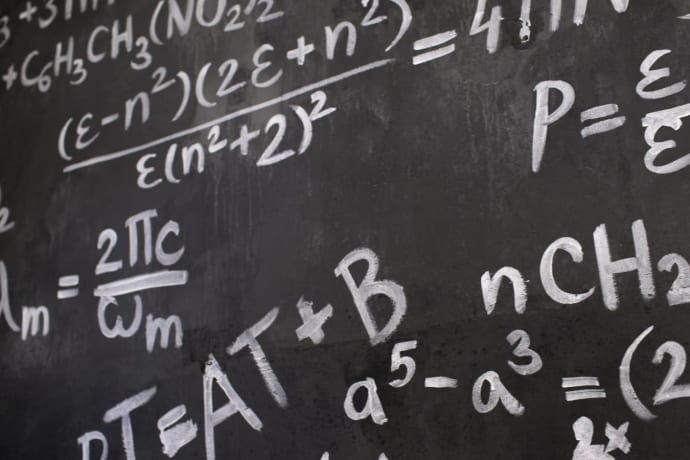 Close-up view of a blackboard filled with complex mathematical equations and formulas.