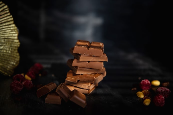 Tempting stack of chocolate pieces accompanied by berries and nuts, perfect for food photography.