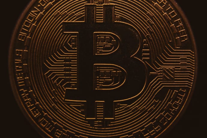 Close-up view of a bitcoin coin showing its intricate, digital design in a warm, dark ambiance.