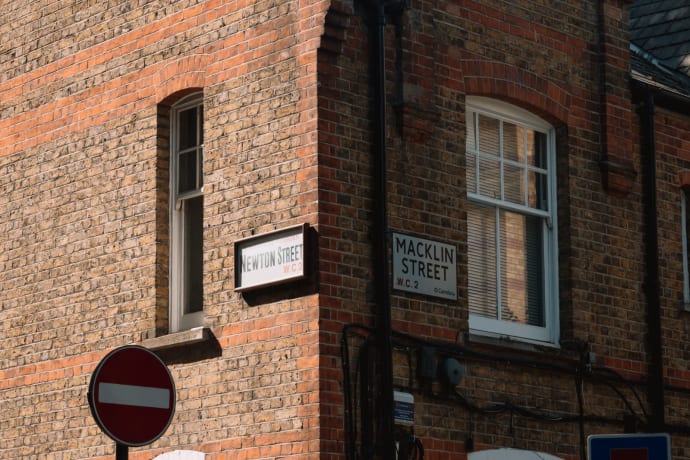 Corner view of a brick building in London with street signs for Newton Street and Macklin Street.