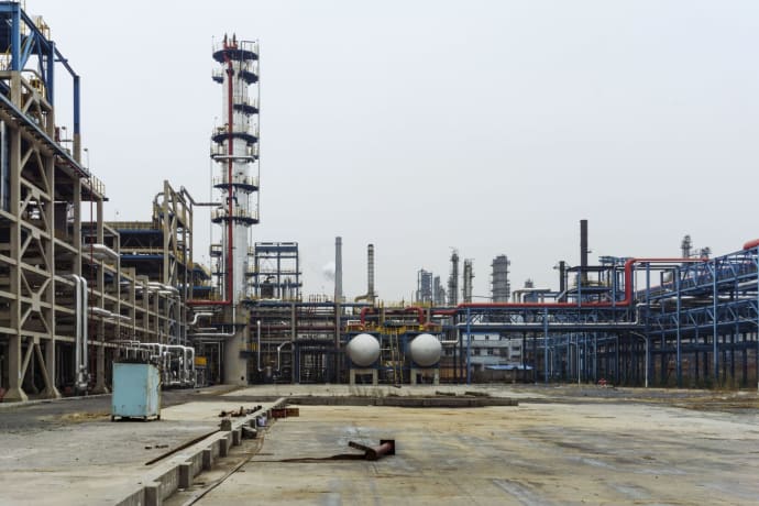 A detailed view of an industrial refinery featuring pipelines and large steel structures.