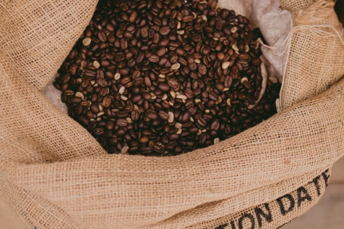 Close-up of roasted coffee beans in a burlap sack, showcasing texture and richness.