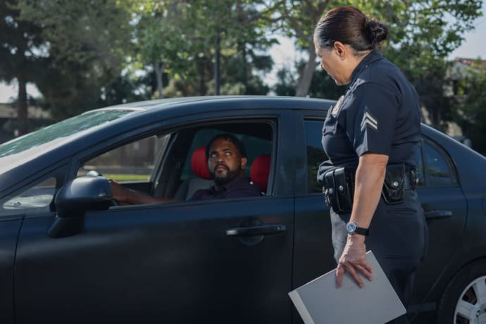 A policewoman discusses a traffic violation with a driver on a sunny day.