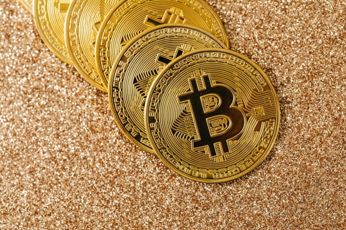 Golden Bitcoin coins arranged on a sparkling glitter surface, symbolizing cryptocurrency and wealth.