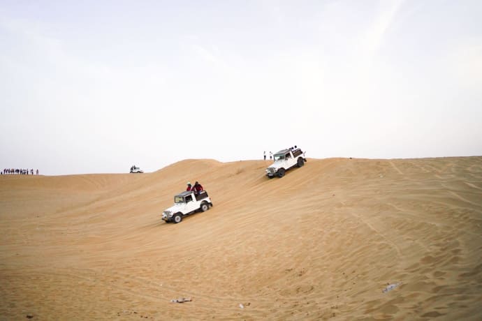 4x4 vehicles navigate rolling desert dunes during a thrilling offroad adventure.
