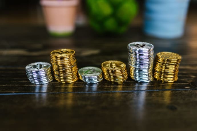 Pile of shiny gold and silver cryptocurrency coins on a wooden table.