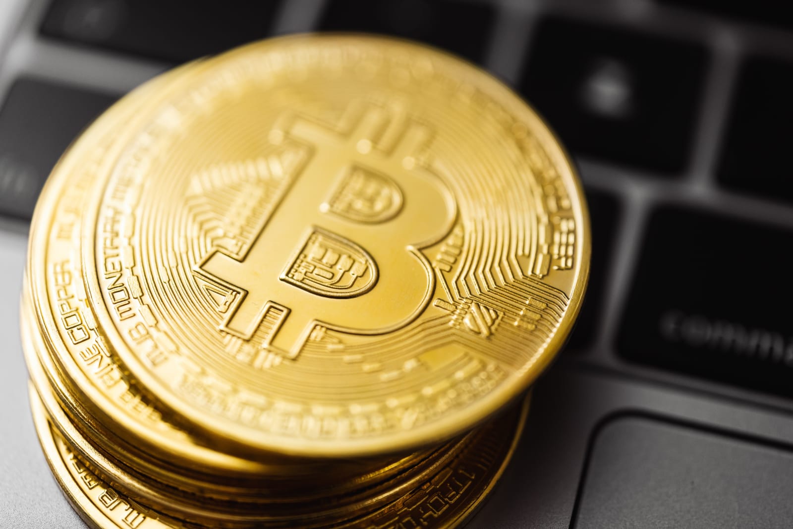 Close-up image of Bitcoin coins stacked on a laptop keyboard, symbolizing digital currency and blockchain technology.