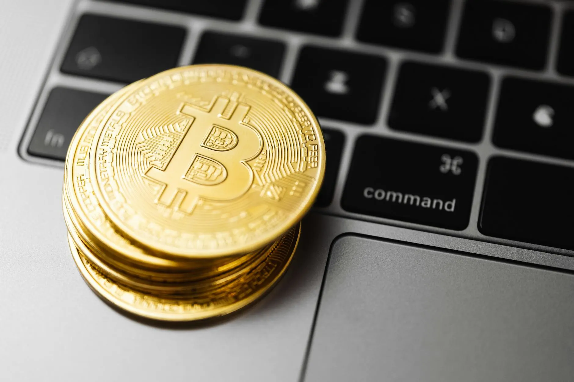 Close-up of gold bitcoin coins on a laptop keyboard, symbolizing digital currency and technology.