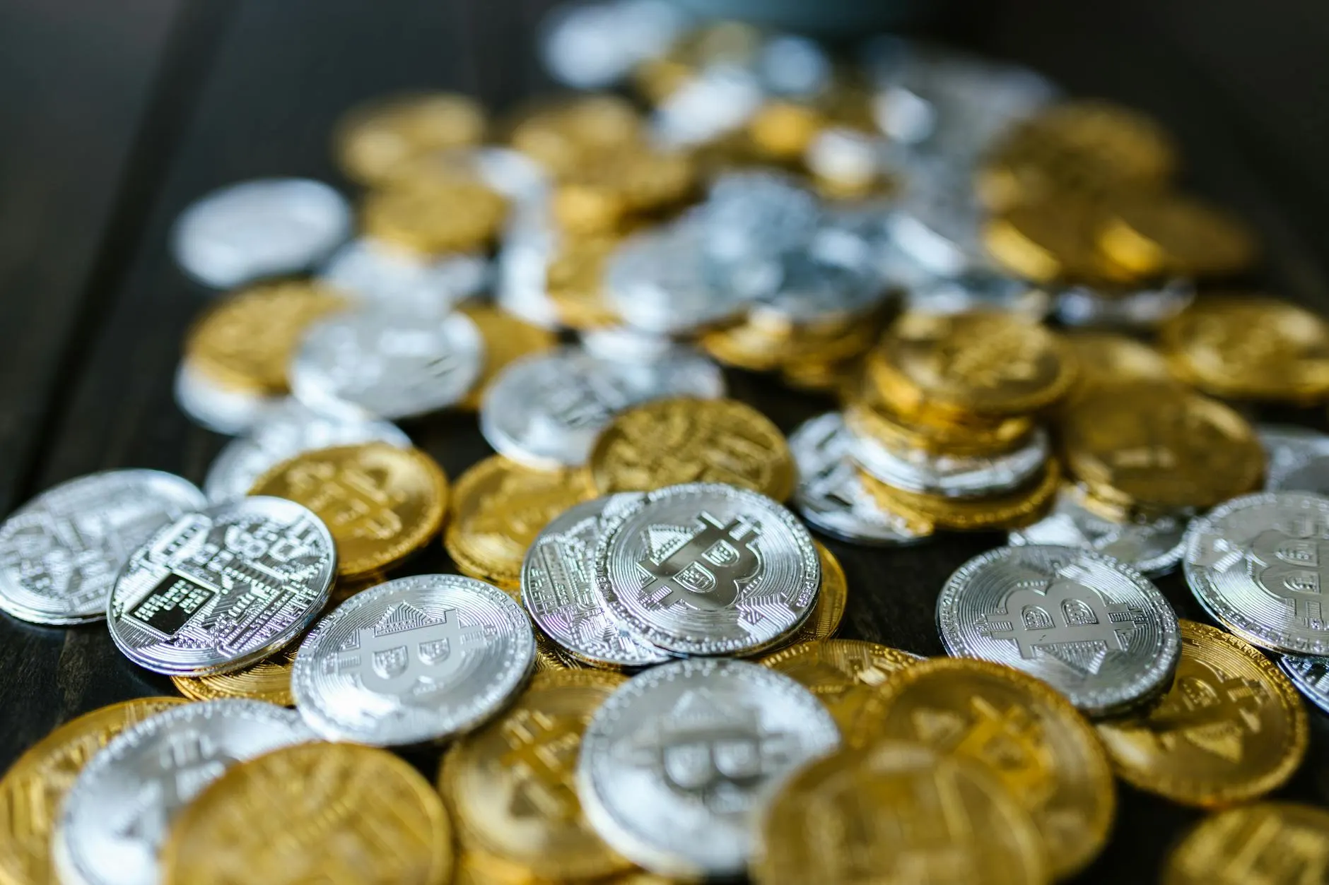 A collection of gold and silver cryptocurrency coins including Bitcoin and Ethereum on a dark surface.