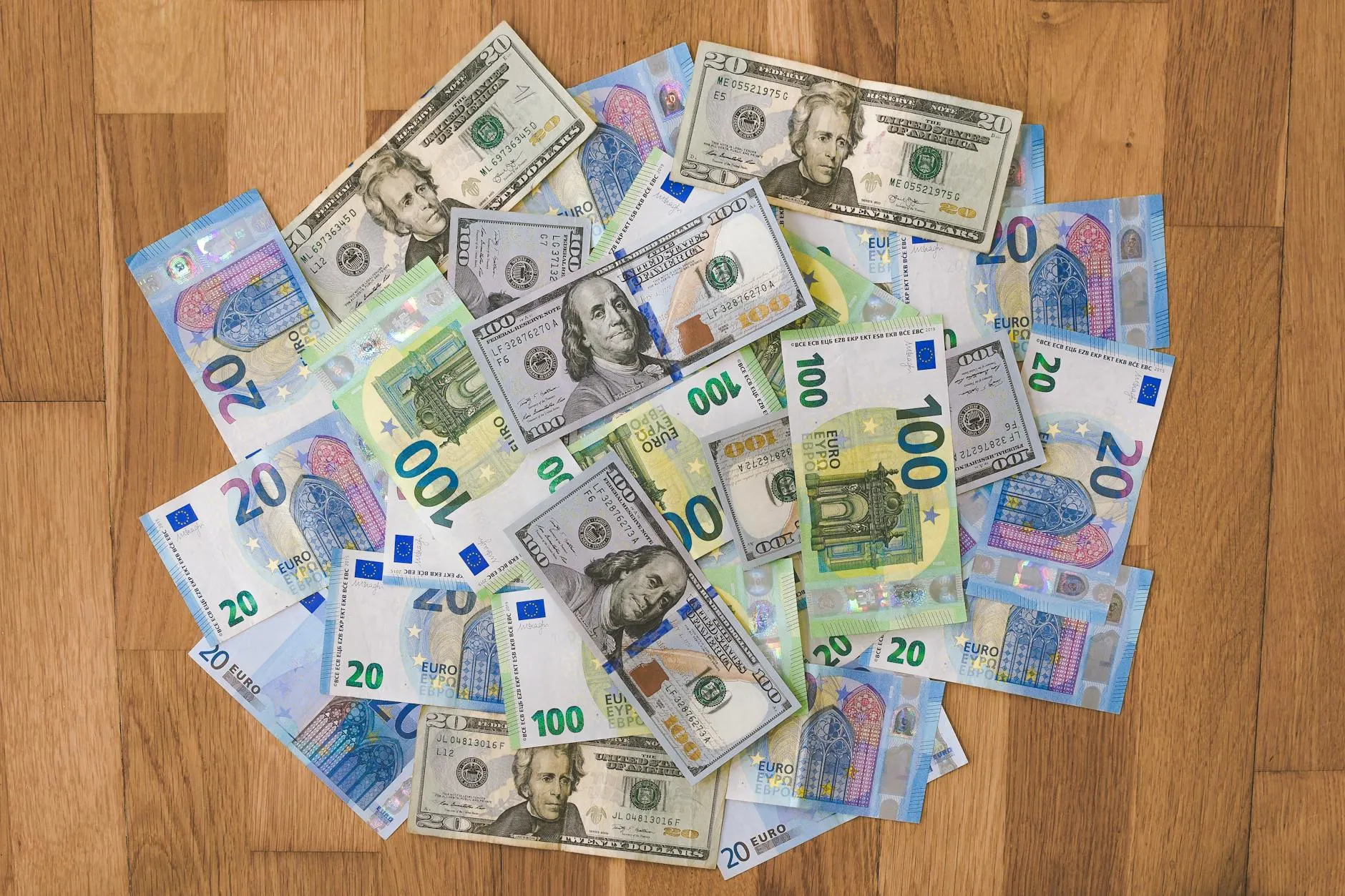 Aerial view of mixed Euro and US Dollar banknotes on a wooden floor, symbolizing global finance.