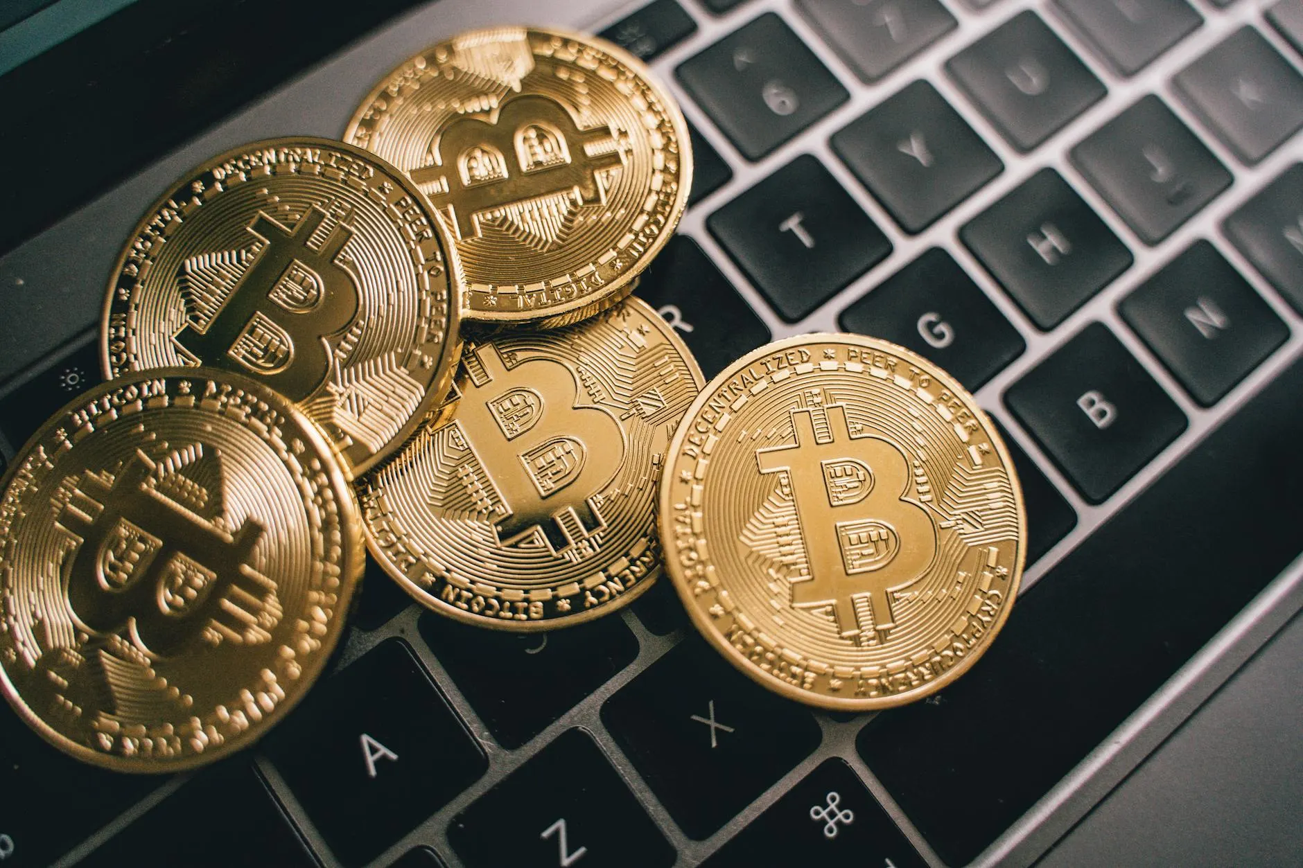 Close-up of multiple Bitcoin coins on a laptop keyboard symbolizing digital currency and cryptocurrency trading.